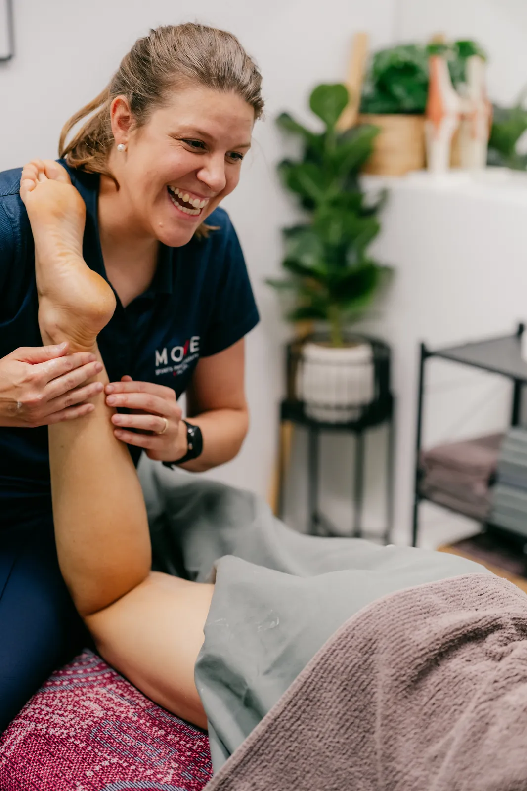 Jess McDonald laughing with a client during hands-on treatment