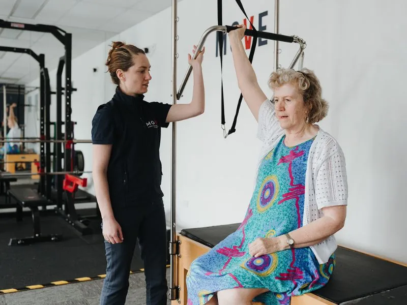 A physiotherapist cueing a reformer core exercise